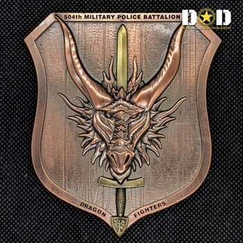 Shield shaped copper challenge coin featuring a 3D dragon head with a sword through it for the 504th Military Police Battalion Dragon Fighters.