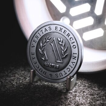 Antiqued silver challenge coin featuring a central number one, laurel wreath, and the Latin text Veritas Exercio Invictus Auctus.