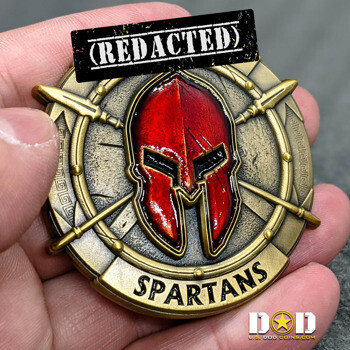 Circular brass challenge coin featuring a red Spartan helmet over crossed spears with 'SPARTANS' text.
