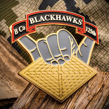 B Co Blackhawks 125th custom challenge coin featuring a hand gesture over a gold lattice design on camouflage fabric.