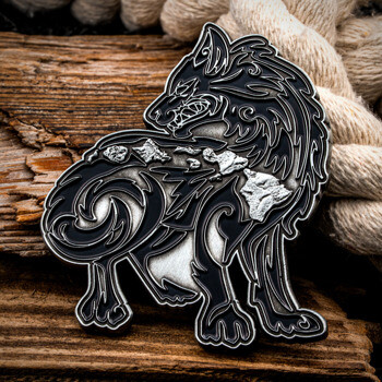 Stylized black enamel wolf lapel pin featuring silver Hawaiian Islands details, resting on driftwood and rope.