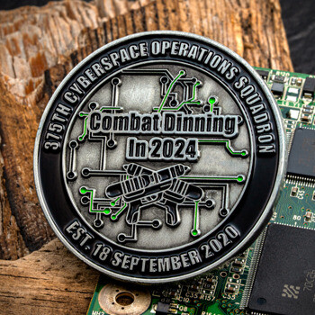 375th Cyberspace Operations Squadron Combat Dinning In 2024 challenge coin over a circuit board.