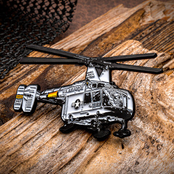 US Air Force Rescue helicopter custom lapel pin resting on wood.