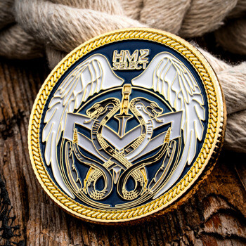 HM2 Select gold and blue challenge coin featuring wings and a caduceus emblem set on a wooden background with nautical rope.