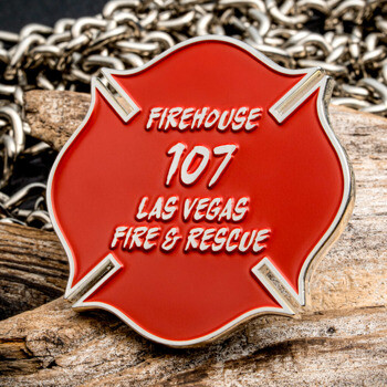 Red Maltese cross Firehouse 107 Las Vegas Fire & Rescue lapel pin displayed on wood with chain backdrop
