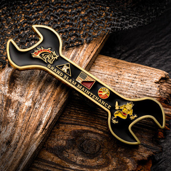 Custom wrench-shaped challenge coin featuring Grand Slam Maintenance text, logos, and brass trim on a black background.