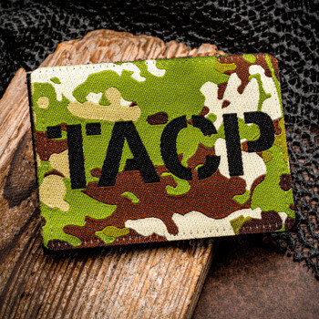 Rectangular military camouflage patch featuring bold black TACP lettering displayed on a wooden surface.