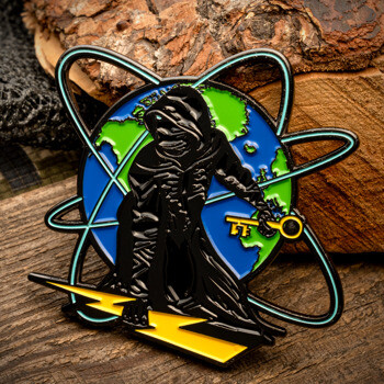 Enamel lapel pin featuring a cloaked figure holding a gold key and standing on a lightning bolt in front of a globe with atomic rings.
