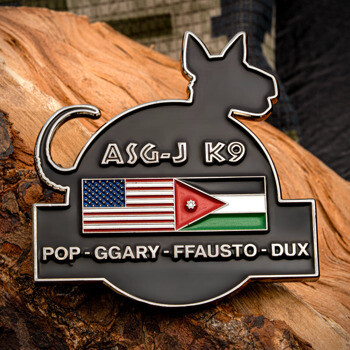 Black dog-shaped challenge coin featuring the US and Jordan flags with text ASG-J K9 and name list.