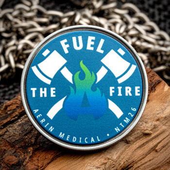 Aerin Medical challenge coin featuring crossed axes and a flame over a blue background on a piece of wood.