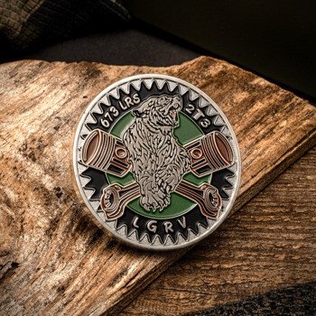 A circular challenge coin featuring a bear and crossed pistons on a gear background, with 673 LRS, 2T3, and LGRV text.