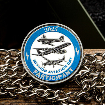 Silver and blue challenge coin featuring three vintage airplanes, dated 2025, for Mission Aviation Day participants.
