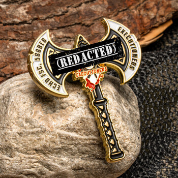 Axe-shaped lapel pin featuring Echo FSC 588BEB Executioners text with a gold and black finish resting on a rock.