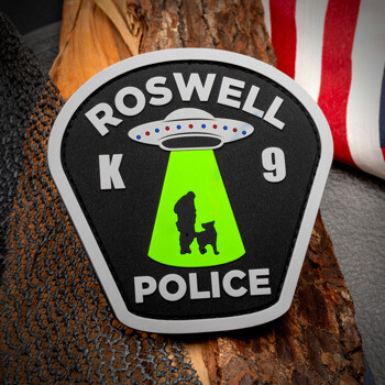PVC patch featuring Roswell Police K9 text with a UFO beam silhouetting a dog and handler, displayed next to an American flag.