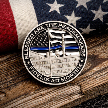 Silver challenge coin with thin blue line flag and building detail resting on wood with an American flag background.