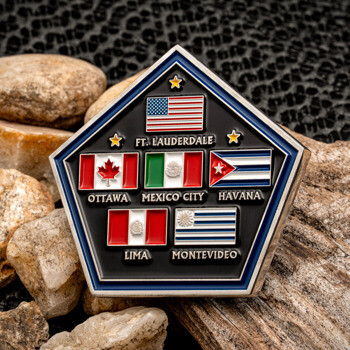 Pentagon shaped challenge coin featuring the flags of USA, Canada, Mexico, Cuba, Peru, and Uruguay with city names on a black background.