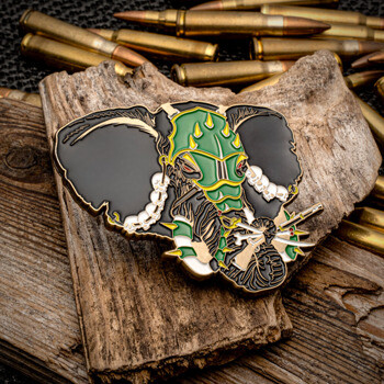 Custom lapel pin featuring an armored war elephant with green helmet and skull tusks, displayed on wood with ammunition background.