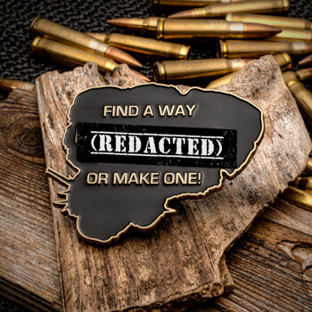 Custom black and gold challenge coin with (REDACTED) text on a piece of wood surrounded by ammunition rounds.