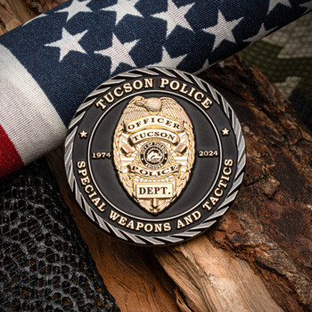 Tucson Police Special Weapons and Tactics challenge coin featuring a gold officer badge on a black background, displayed with an American flag.