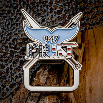 Whale tail and harpoon themed bottle opener challenge coin with 947 FRST text and American flag patterns.