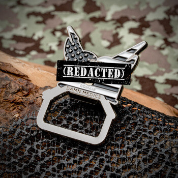 A custom bottle opener challenge coin featuring a winged design with an American flag pattern and the text Damn Medics Roman.