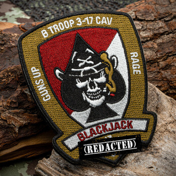 Embroidered military patch for B Troop 3-17 CAV featuring a skull inside a spade on a red and white shield, resting on a log.