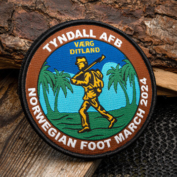 Circular embroidered patch for the Tyndall AFB Norwegian Foot March 2024 featuring a rucking soldier, palm trees, and mountain background.