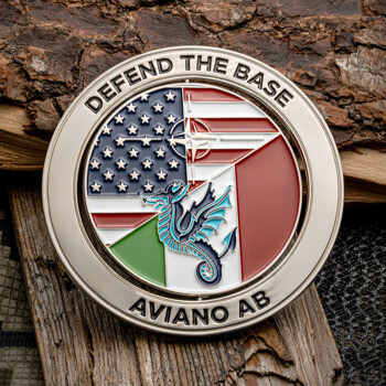 Silver challenge coin with American and Italian flags, NATO star, and a seadragon emblem, inscribed with Defend the Base and Aviano AB.