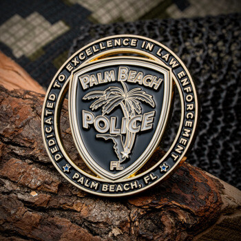 Gold and black Palm Beach Police challenge coin featuring a palm tree emblem resting on a tree branch.