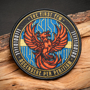 Circular embroidered patch featuring an orange phoenix over a blue circuit board background with binary code and the text 'The First Few'.