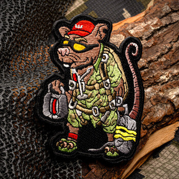 Embroidered patch featuring a rat character in tactical gear wearing a red hat and sunglasses, displayed on a wooden log with camouflage mesh.