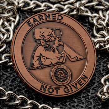 Antique bronze challenge coin featuring a tactical operator and Georgia Peace Officer Standards and Training Council seal, resting on a silver chain.