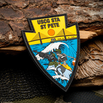 Arrowhead-shaped PVC patch for USCG STA ST PETE featuring a skeleton riding a dolphin under the Sunshine Skyway Bridge.
