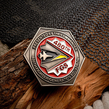 Hexagonal silver challenge coin with 480th FGS emblem and fighter jet design on a red background.