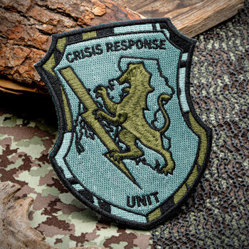 Embroidered shield-shaped patch for Crisis Response Unit featuring a lion holding a lightning bolt on a light blue background.
