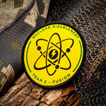 Circular embroidered patch for Nuclear Disablement Team 2 Fusion featuring a yellow background with a black atom symbol and lightning bolt.