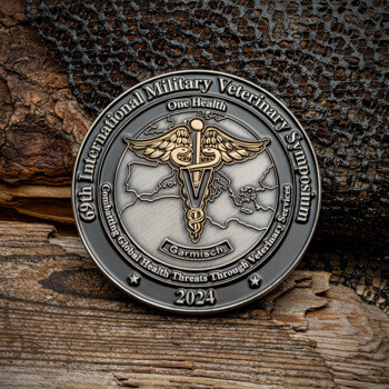 Antiqued silver challenge coin for the 69th International Military Veterinary Symposium featuring a gold caduceus over a world map.