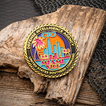 Defense Intelligence Agency CIO Miami Vice challenge coin with a skyline, palm trees, and sunset design on a gold textured edge.