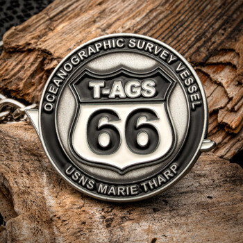 A round silver and black challenge coin featuring a Route 66 shield design for Oceanographic Survey Vessel USNS Marie Tharp T-AGS 66.