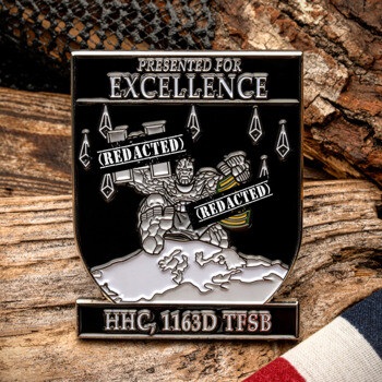 Shield-shaped challenge coin featuring a stone character with redacted text, labeled HHC, 1163D TFSB and presented for excellence.