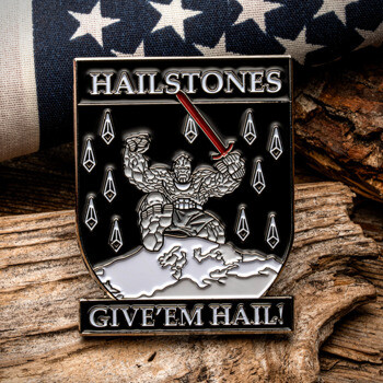 Shield-shaped lapel pin featuring a stone giant holding a red sword under falling hailstones, with 'Hailstones' and 'Give 'Em Hail!' text.