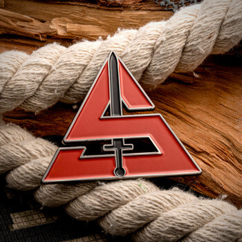Triangular red enamel lapel pin featuring a stylized delta shape and a central sword icon, resting on a nautical rope.