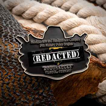 Custom cut-out challenge coin for Headquarters and Headquarters Company 18th Military Police Brigade Roughnecks Vilseck Germany, set on a wooden log.