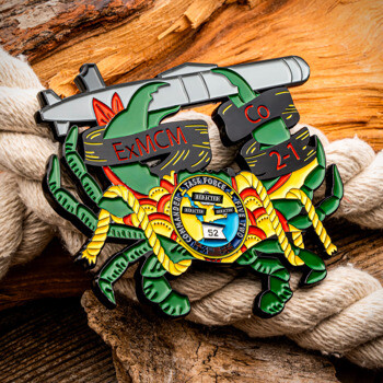 Custom cut-out challenge coin shaped like a green crab carrying a submarine and navy ropes on a wood and rope background.