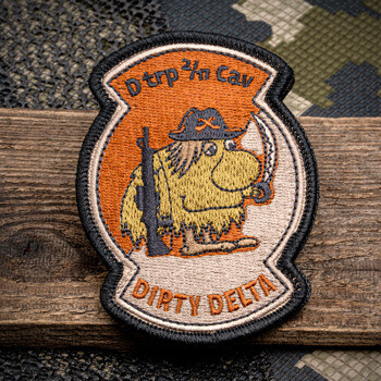 Embroidered military patch featuring 'D Trp 2/17 Cav' and 'Dirty Delta' text, depicting a cartoon caveman figure holding a rifle and sword.