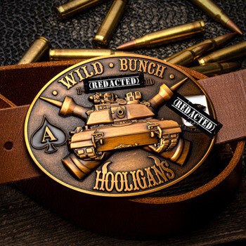 Oval antique bronze belt buckle featuring a military tank design with Wild Bunch Hooligans text, shown on a leather belt with bullets in the background.