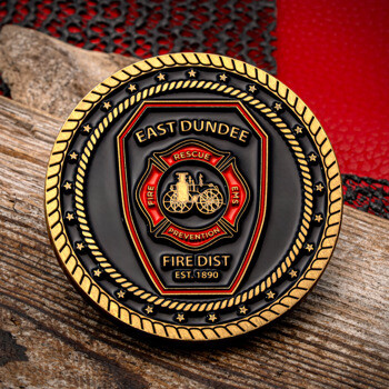 East Dundee Fire Dist custom challenge coin featuring a black background, gold rope border, and a red Maltese cross rescue emblem with an antique fire engine.