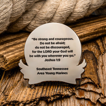 Custom silver lapel pin featuring Joshua 1:9 scripture text and Southeast Tennessee Area Young Marines engraving, set against wood and rope elements.