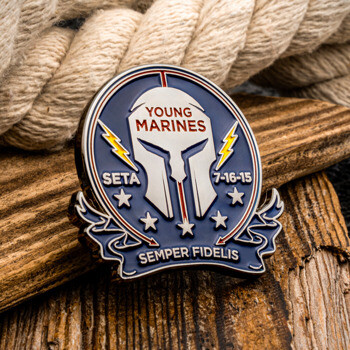 Custom shield-shaped lapel pin for Young Marines featuring a Spartan helmet design, lightning bolts, and the motto Semper Fidelis on rustic wood.