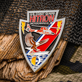 Arrowhead-shaped U.S. Coast Guard HITRON Jacksonville challenge coin featuring a helicopter, eagle, and lightning bolts on a camouflage background.